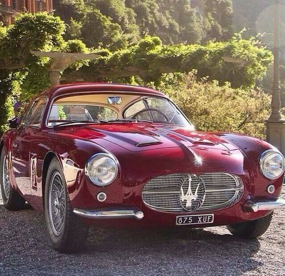 A classic Maserati coupe painted red.